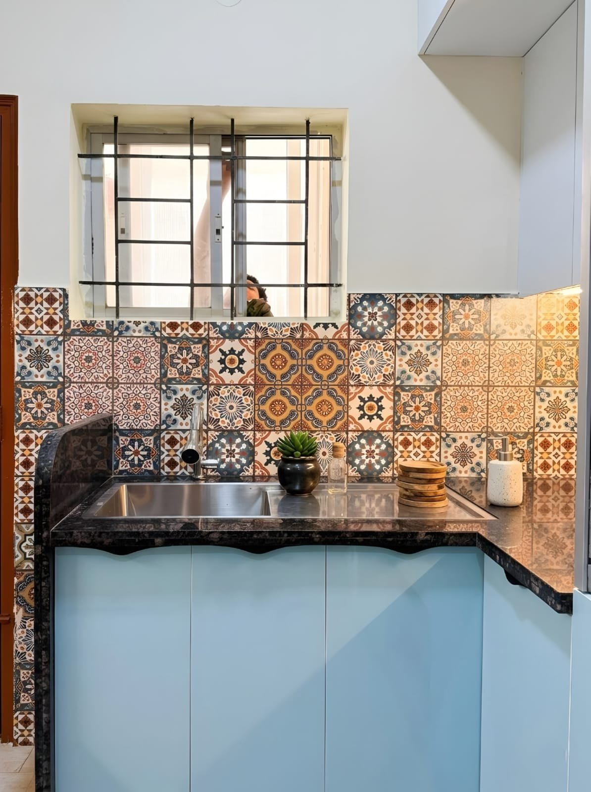 Sky-blue kitchen with colourful Moroccan backsplash tiles and a granite counter
