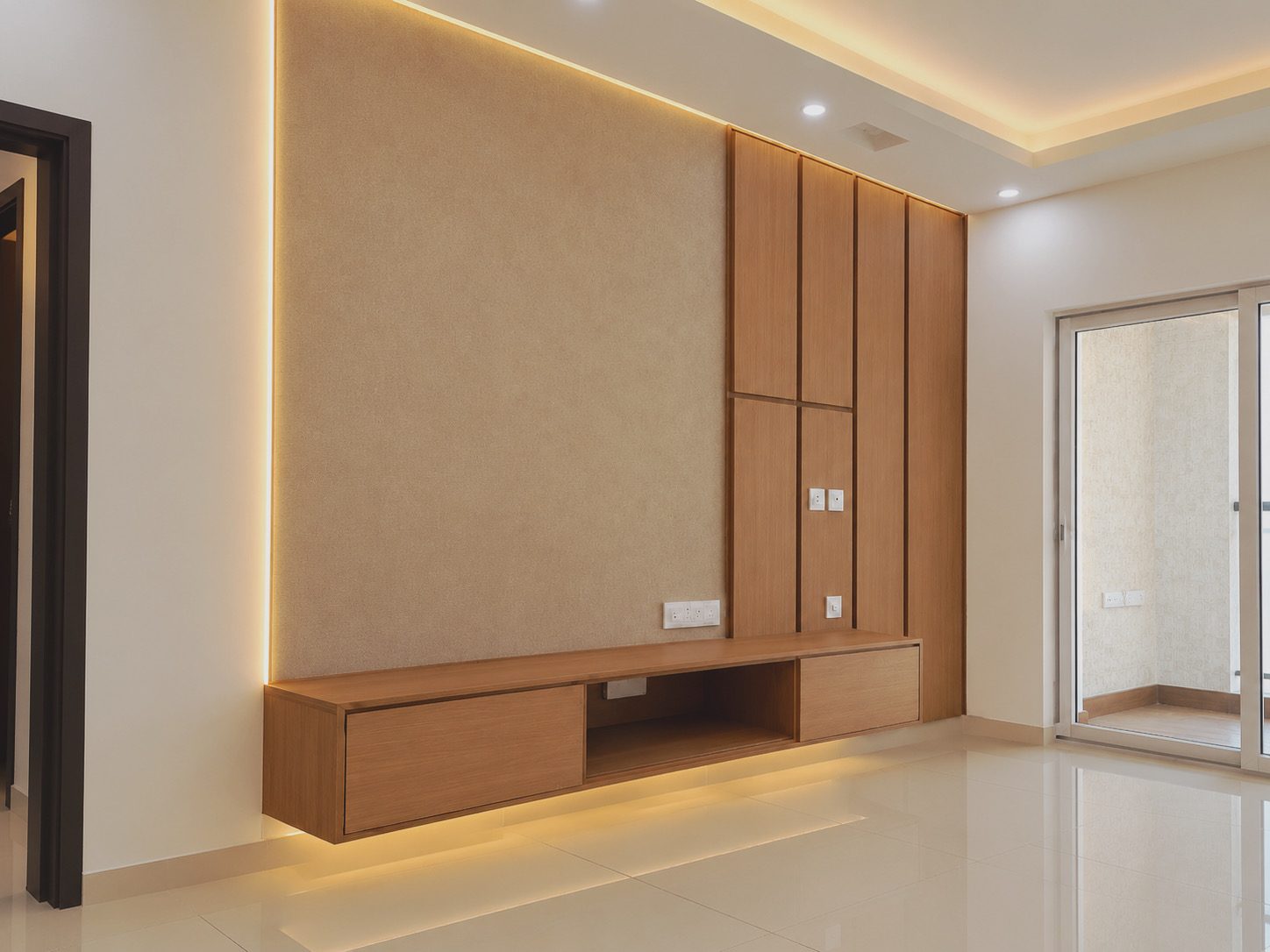 Living room TV unit design with backlit fabric panel, oak vertical panels and floating console in a 2 BHK on Sarjapur Road, Bangalore